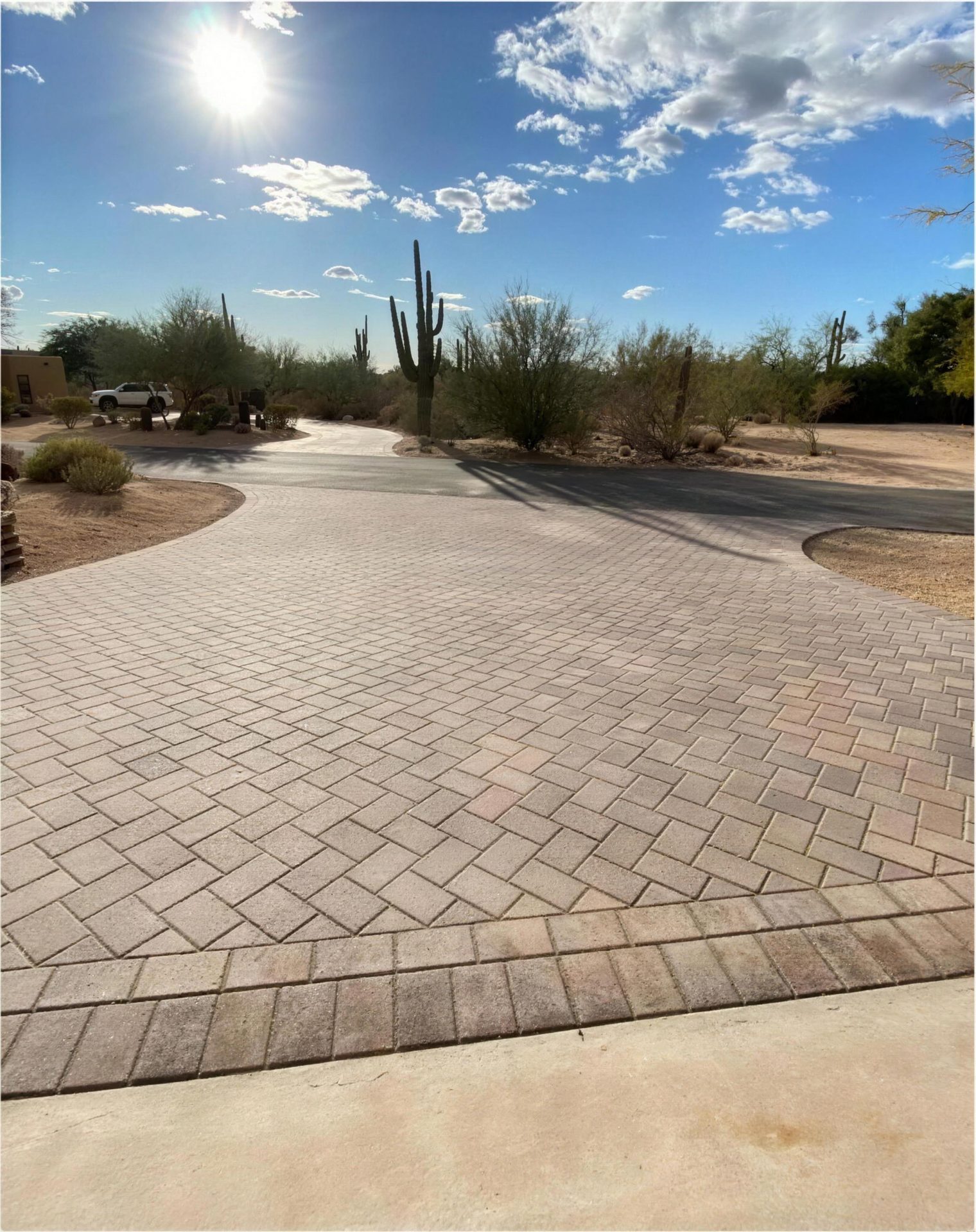 After: herringbone paver driveway with a double border, saguaros behind