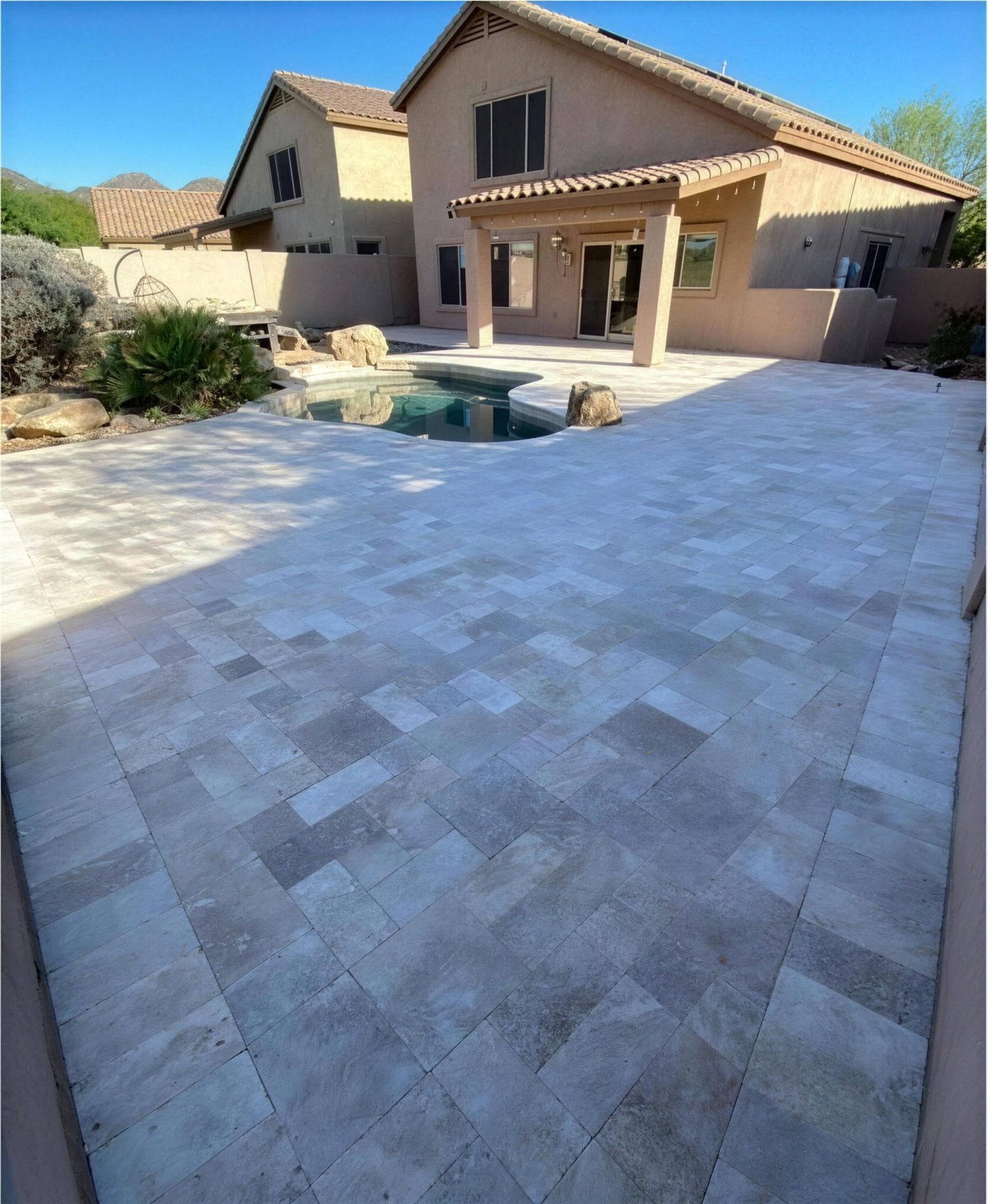 After: the same backyard wrapped in silver travertine decking
