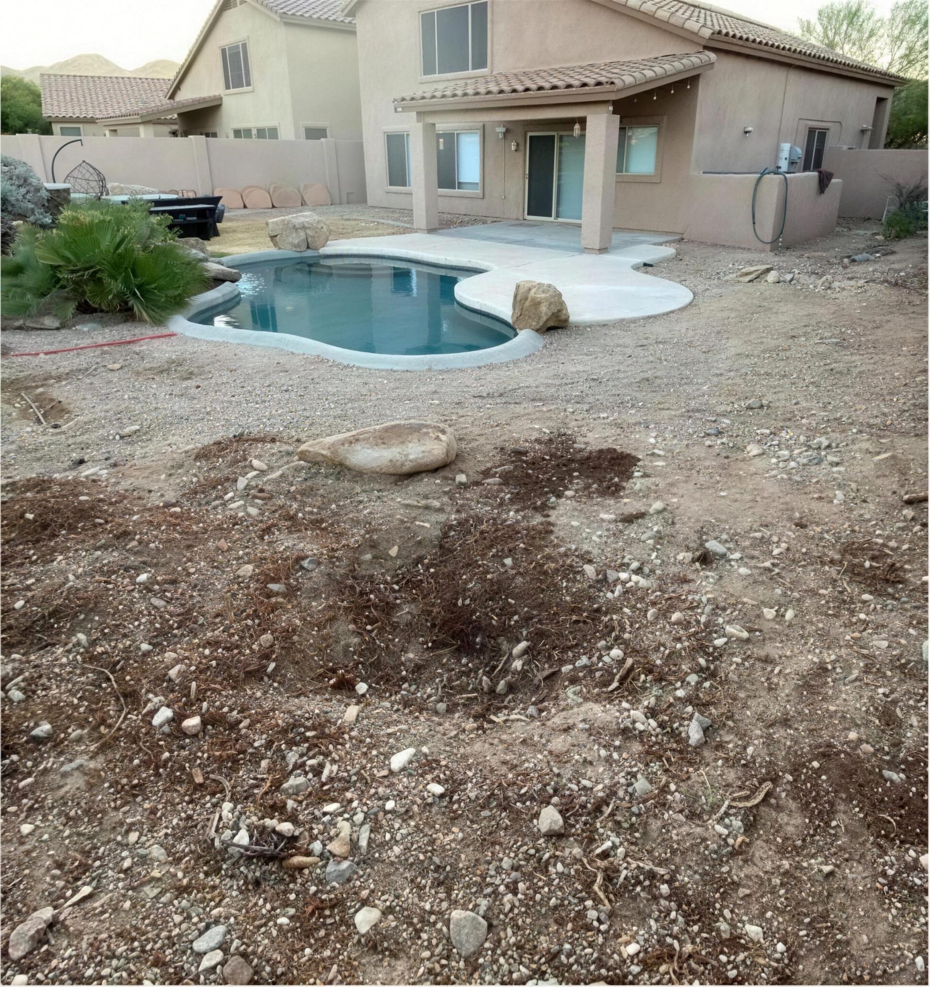 Before: dirt and rock around a small backyard pool