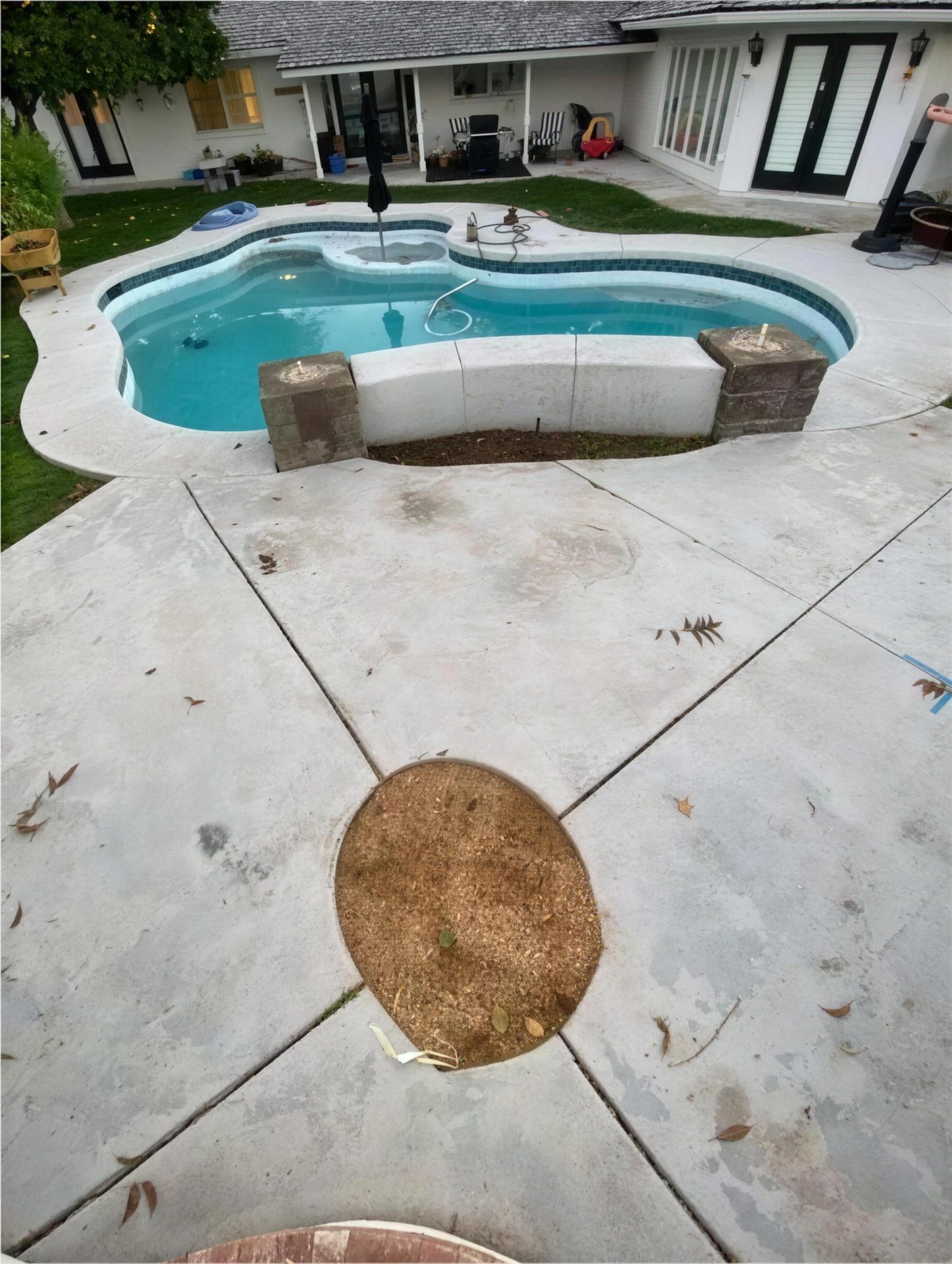 Before: cracked concrete pool deck with a dirt planter circle