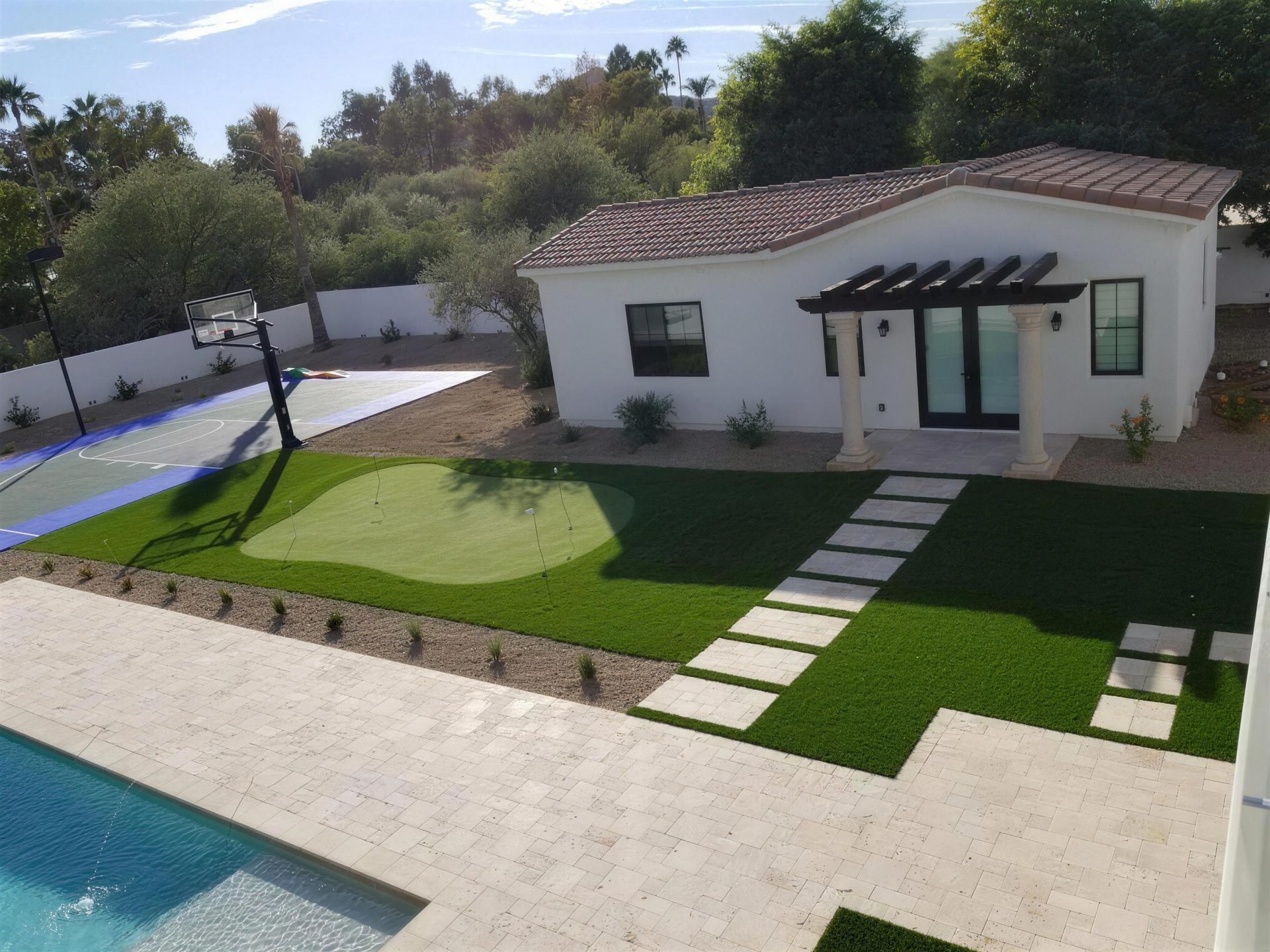 Aerial view of a full backyard build, travertine deck and stepping pads with artificial turf
