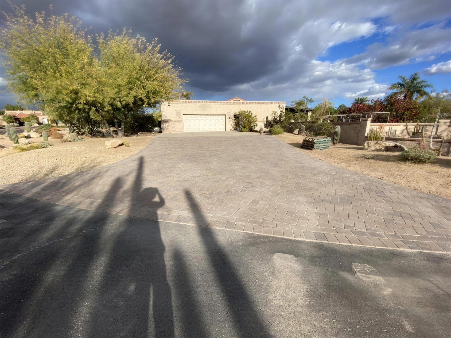 Wide paver driveway under dramatic monsoon-season clouds
