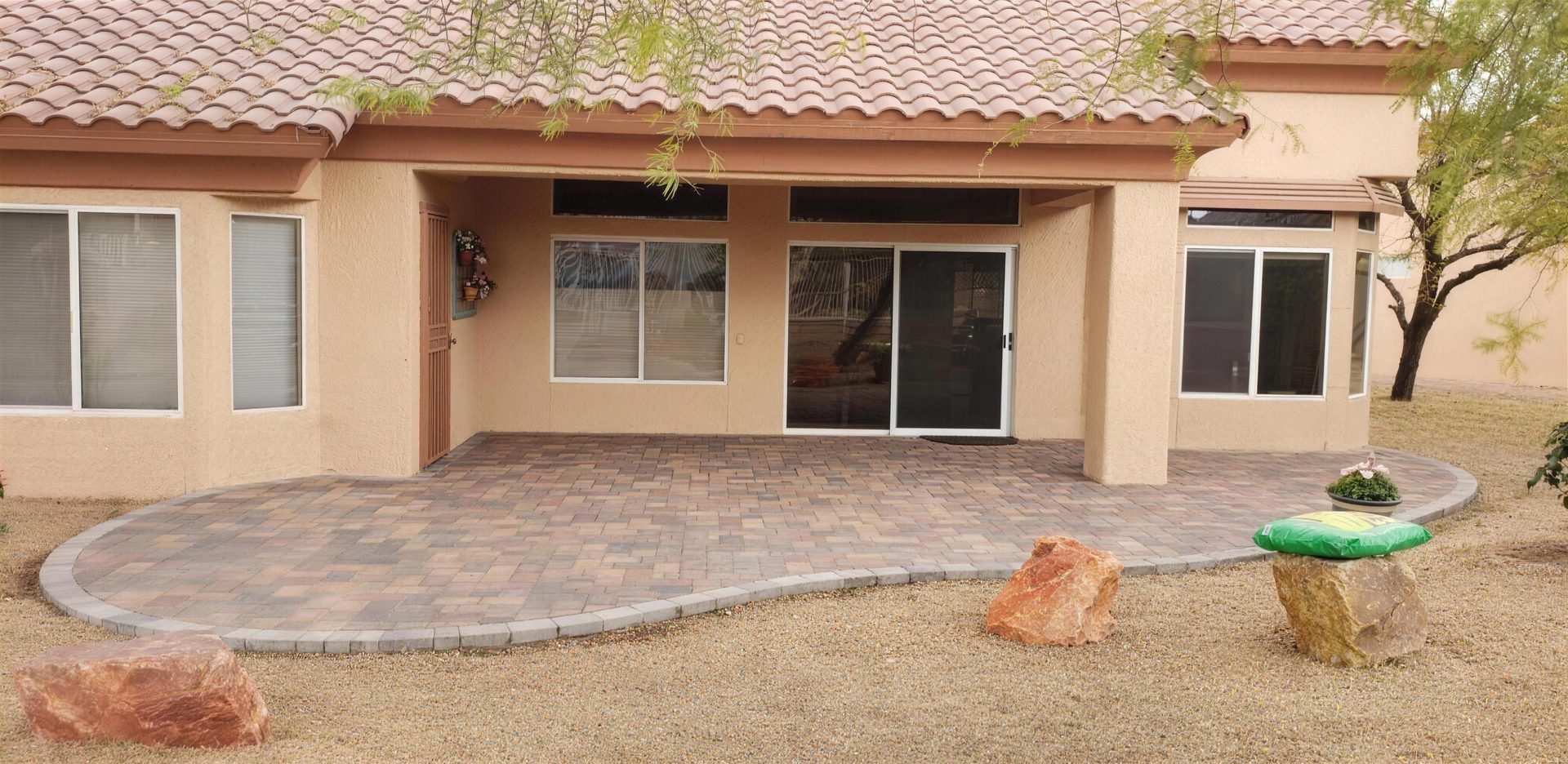 Curved paver patio with a contrasting border behind a Valley home