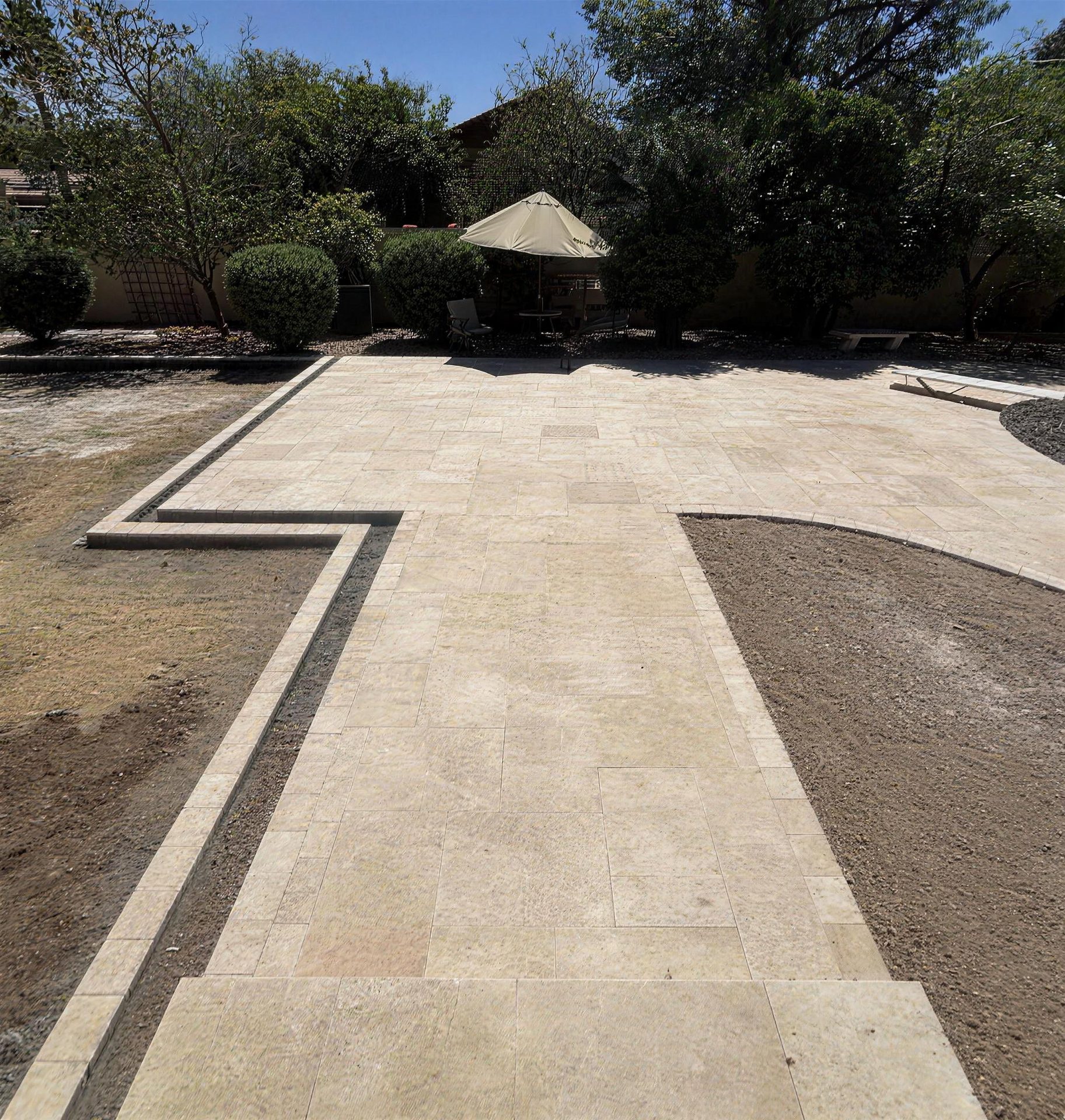 Travertine paver patio with a shade umbrella