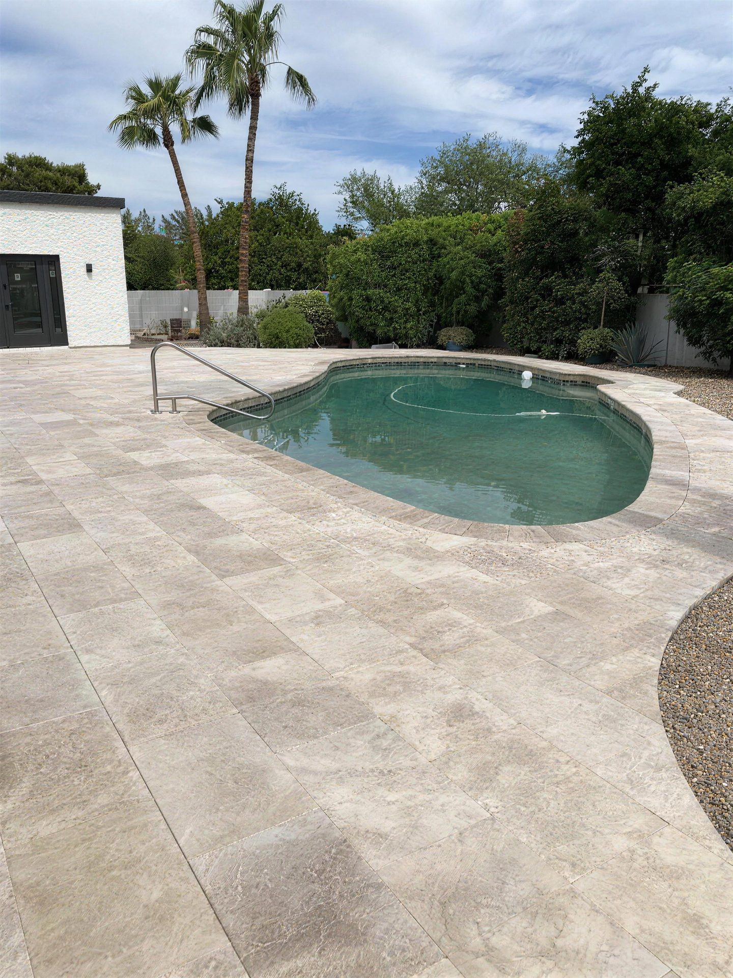 Travertine pool deck and handrail framed by palms
