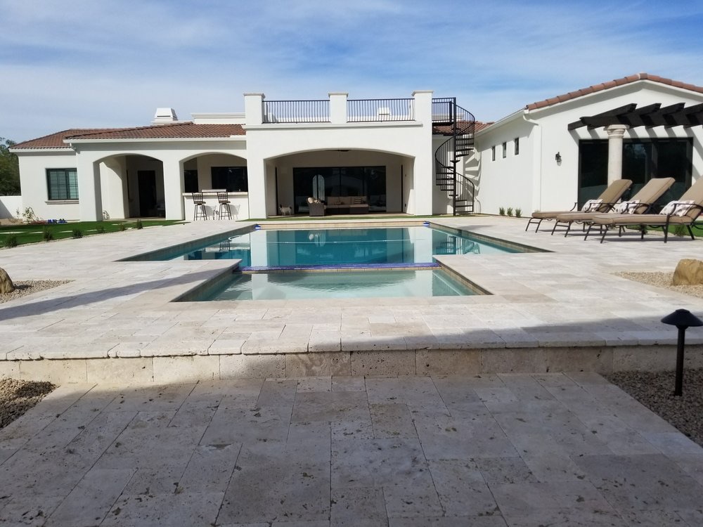 Travertine pool deck around a backyard pool