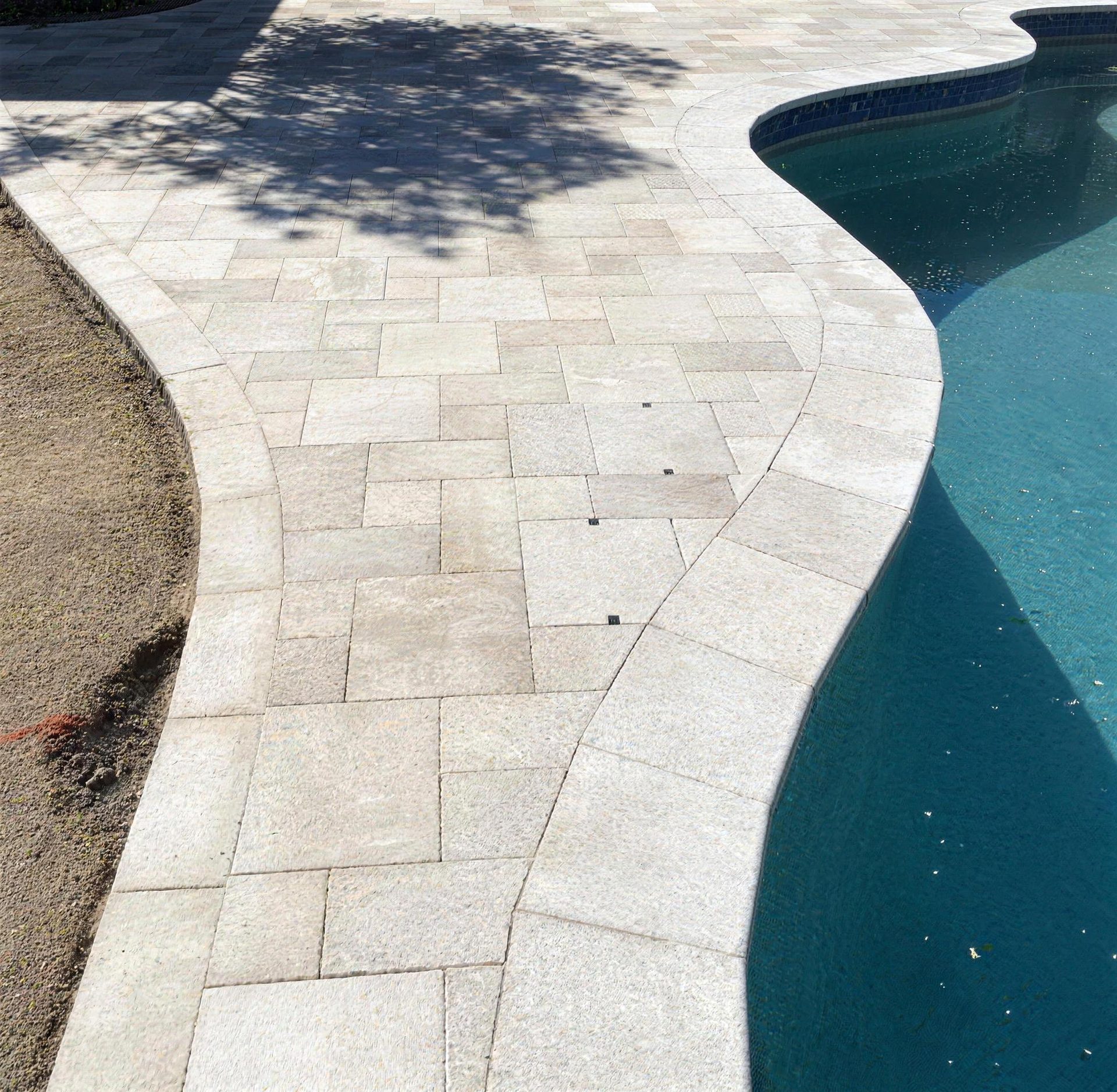 White travertine pool deck curving around the water