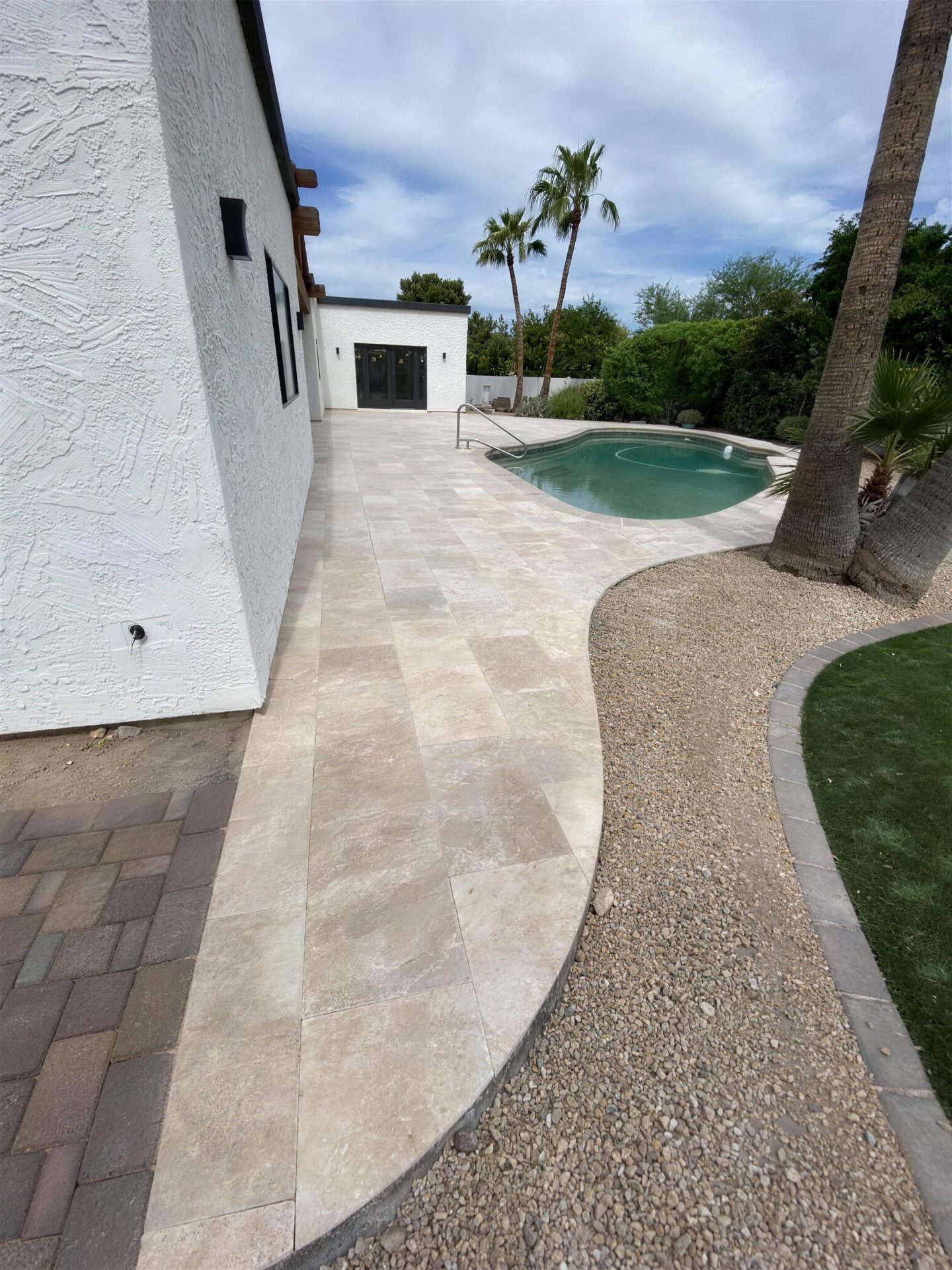 Travertine walkway running along the house to the pool