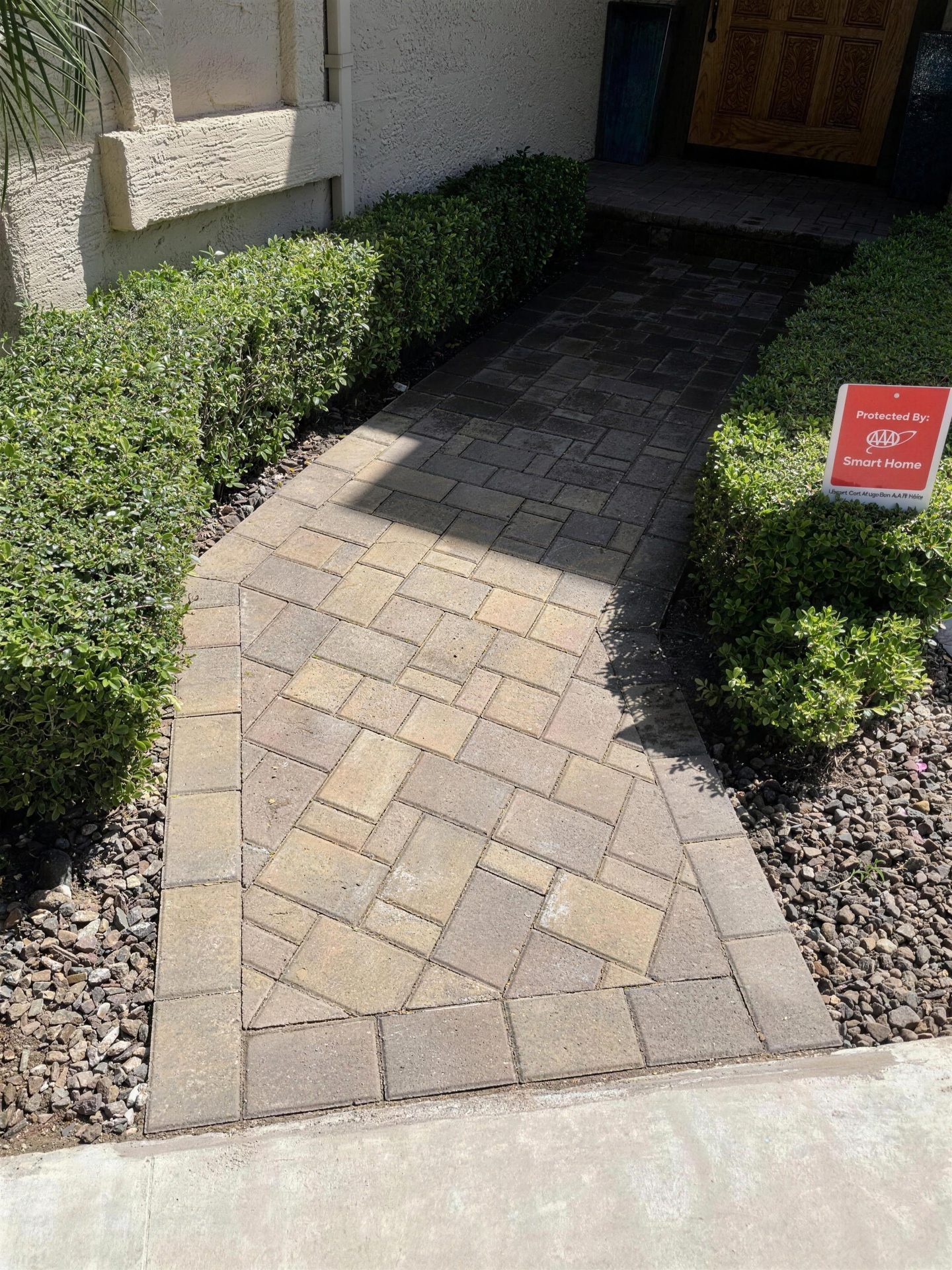 Paver front walkway with a diamond-pattern inlay between hedges